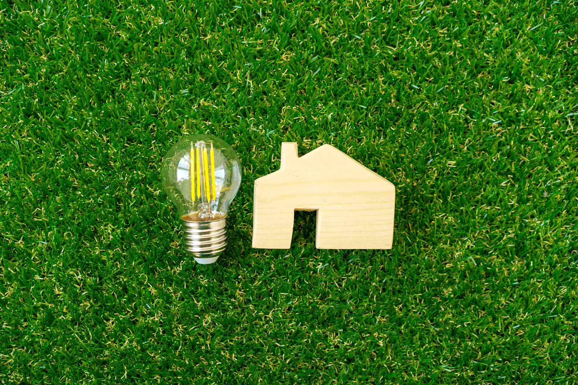 wooden house model and lightbulb on green backgrou 2023 11 27 05 35 59 utc